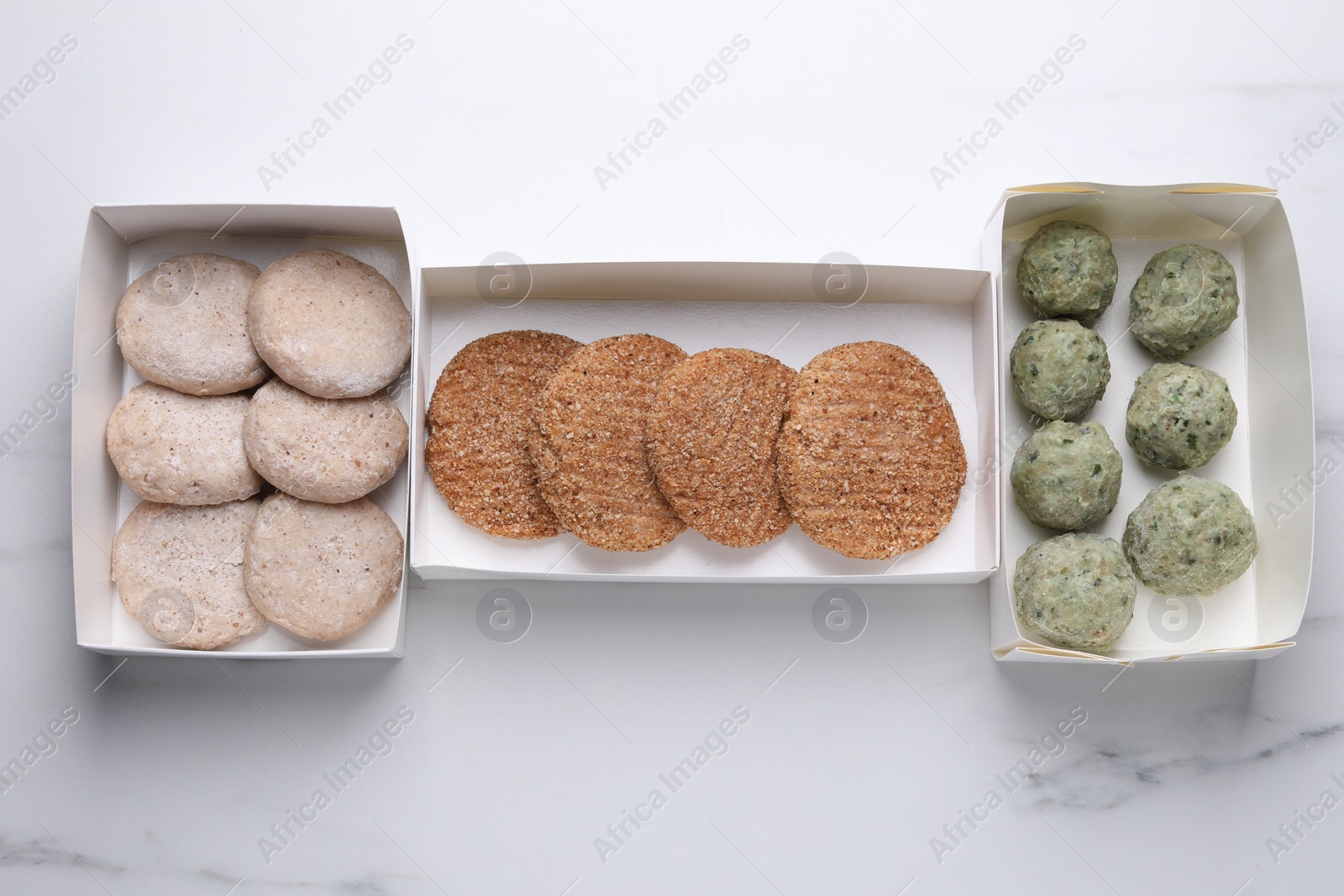 Photo of Different raw vegan meat products on white marble table, flat lay