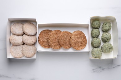 Photo of Different raw vegan meat products on white marble table, flat lay