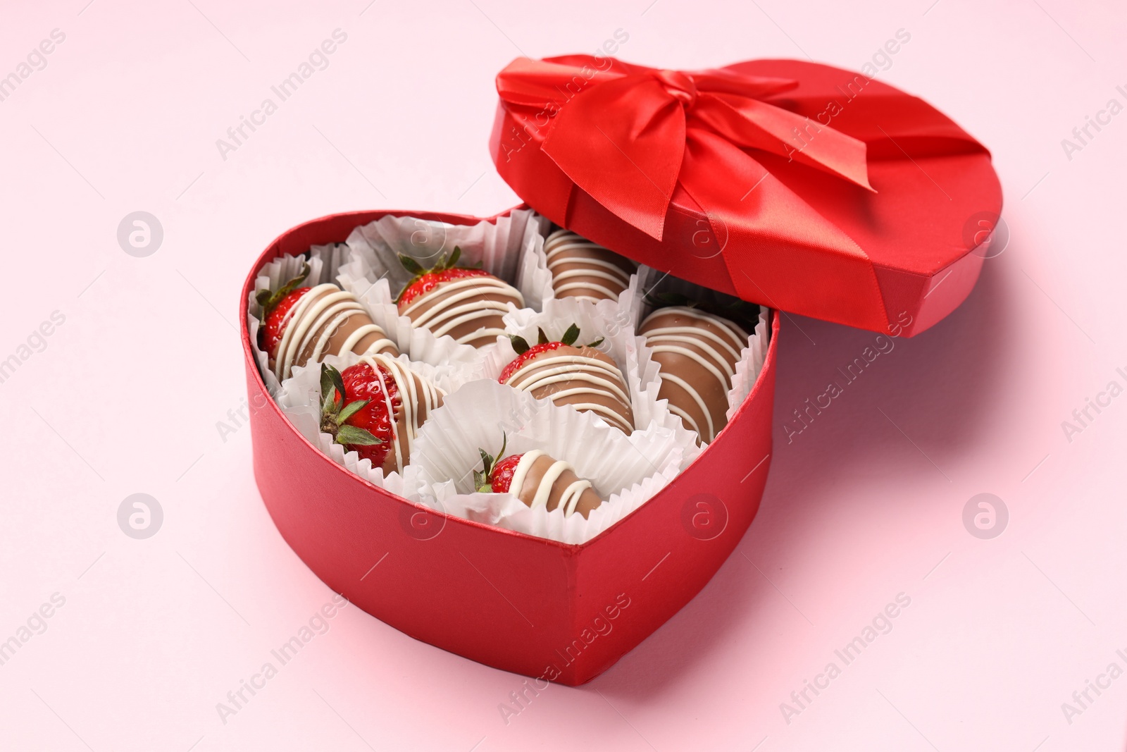 Photo of Heart shaped box with delicious chocolate covered strawberries on pink background