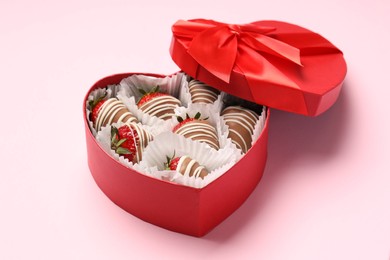 Heart shaped box with delicious chocolate covered strawberries on pink background