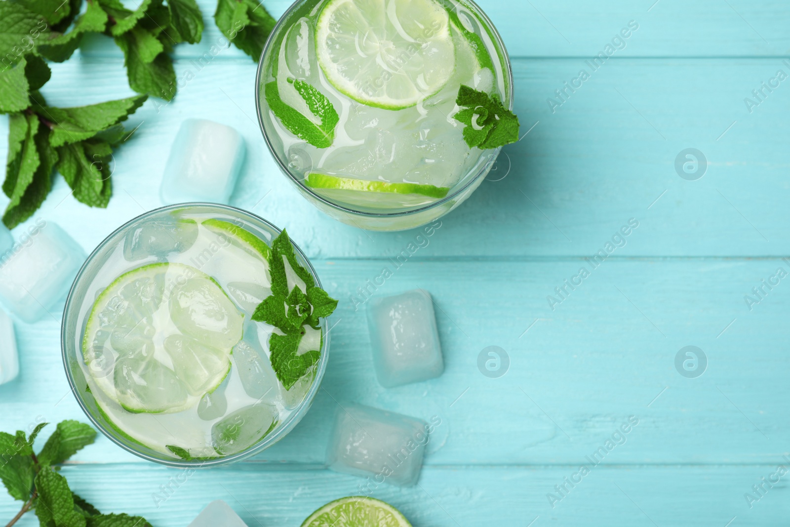 Photo of Flat lay composition of cocktail with vodka, ice and lime on blue wooden table. Space for text