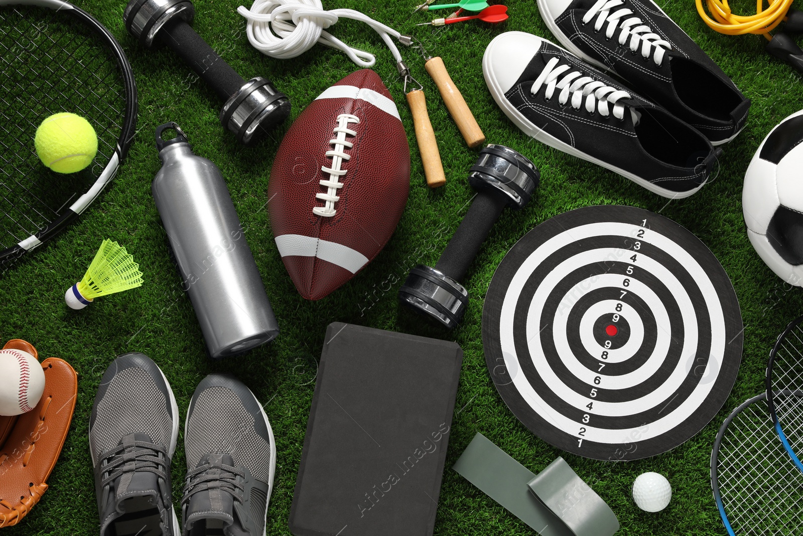 Photo of Different sports equipment on green grass, flat lay