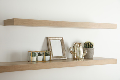 Wooden shelves with photo frame and decorative elements on light wall