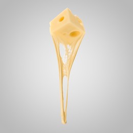 Tasty cheese stretching in air on grey background