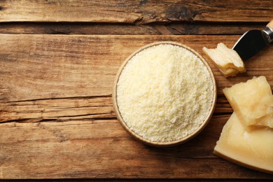 Flat lay composition with grated parmesan cheese and knife on wooden table. Space for text