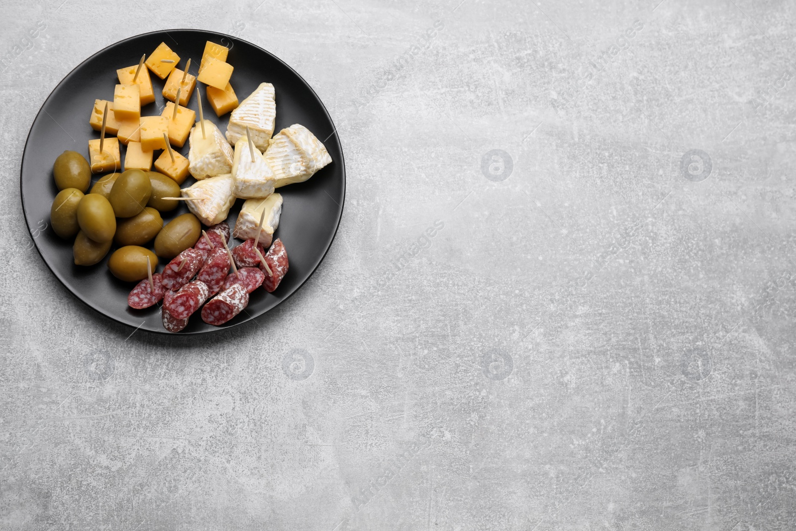 Photo of Toothpick appetizers. Pieces of cheese, sausage and olives on light grey table, top view. Space for text