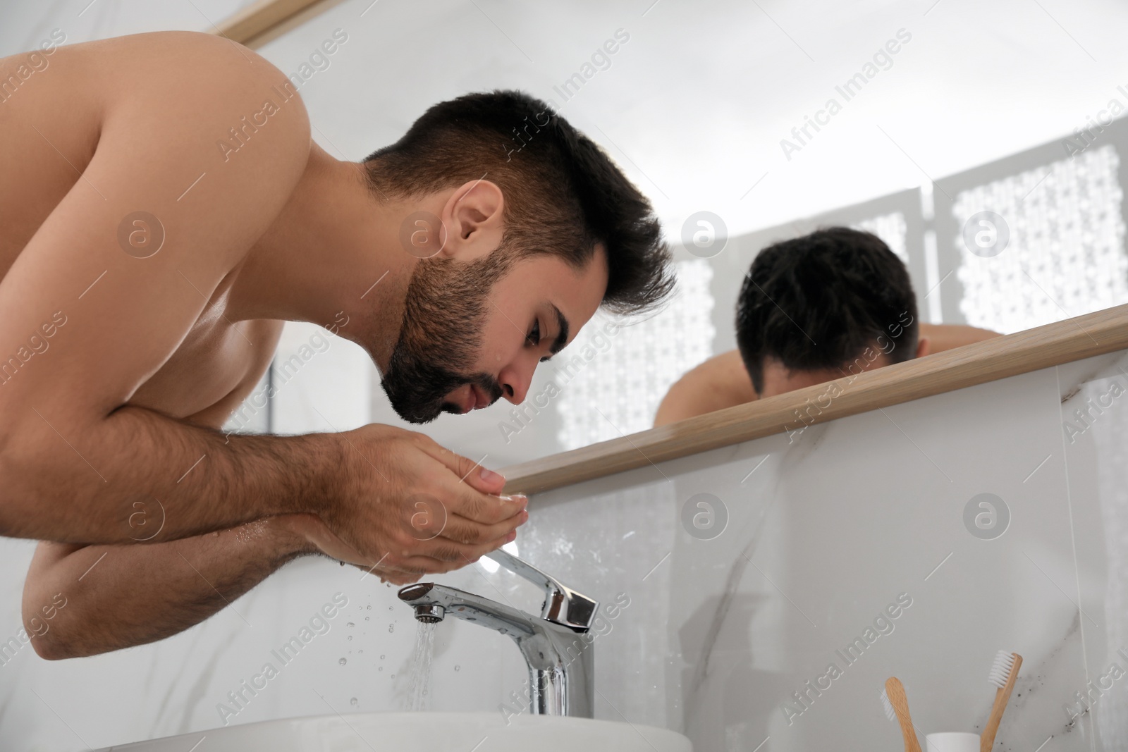 Photo of Handsome young man washing after shaving in bathroom