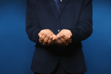 Businessman holding something on color background, closeup of hands