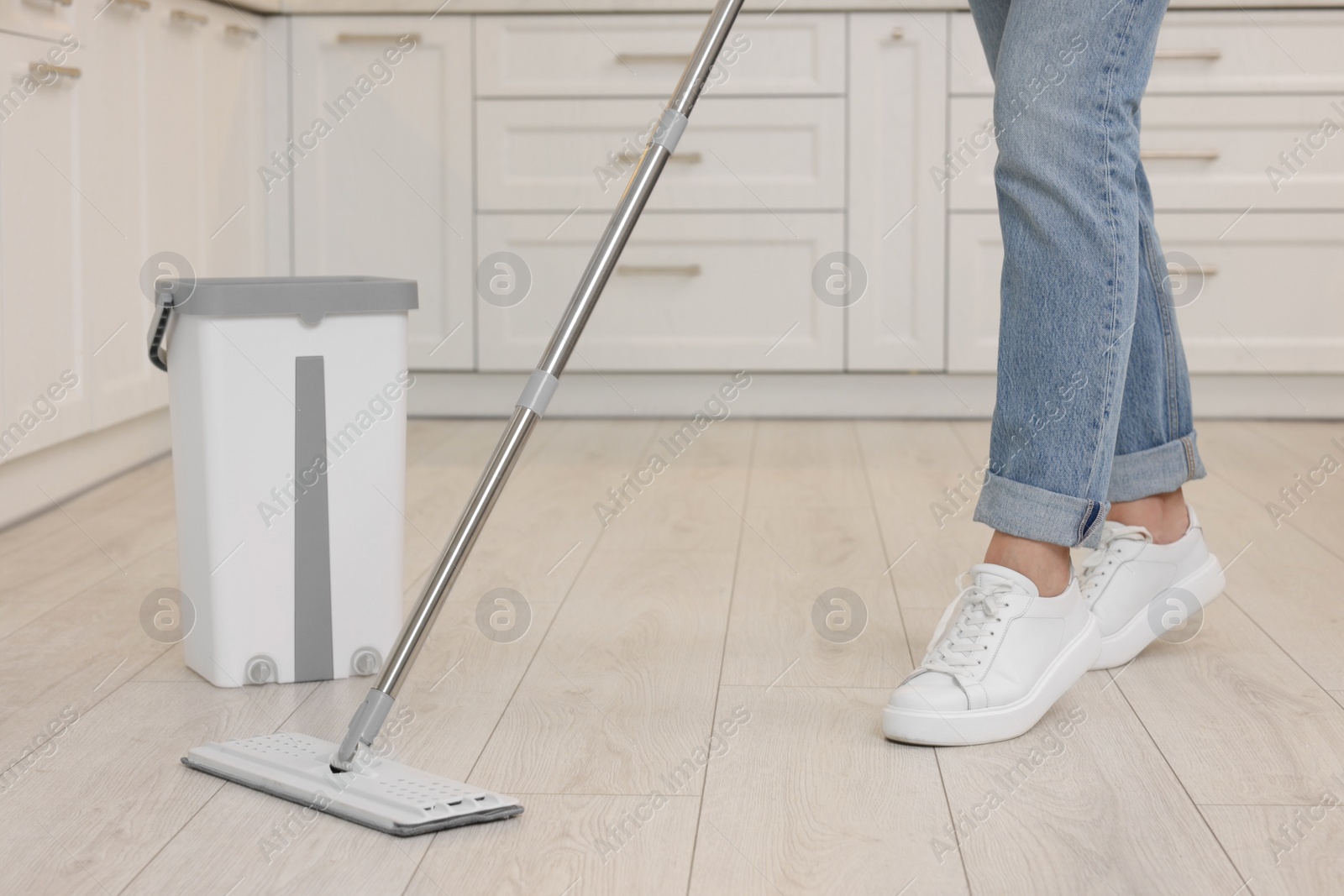 Photo of Woman cleaning floor with mop indoors, closeup