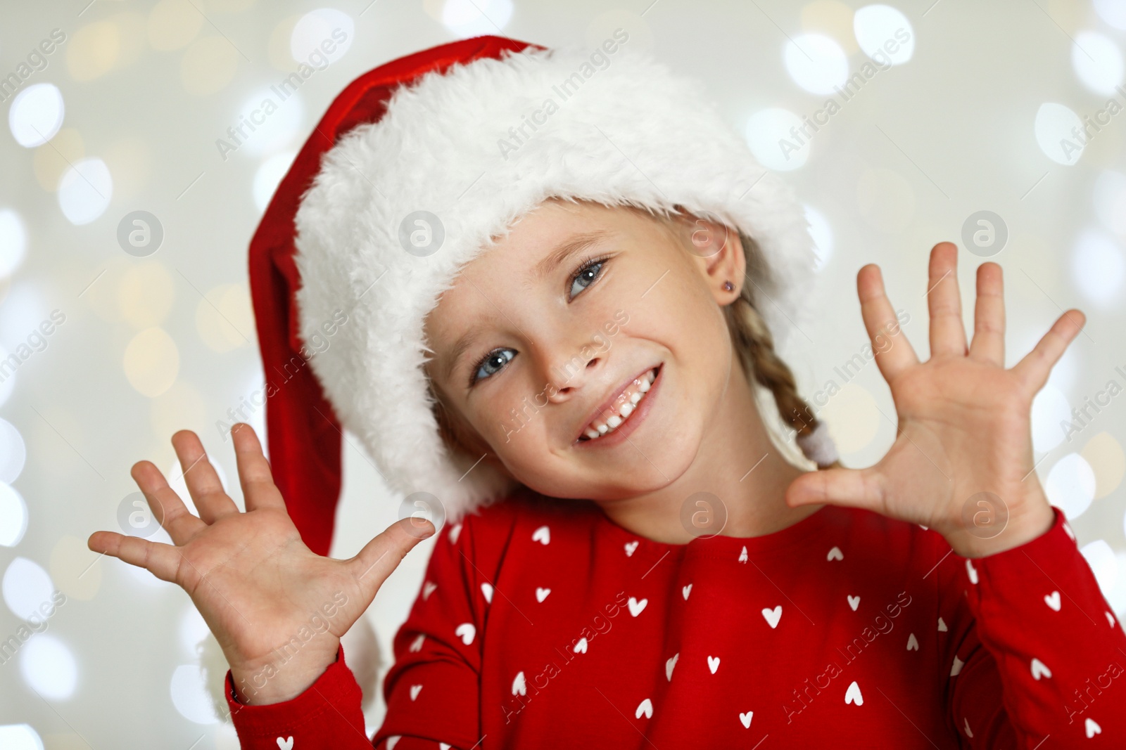 Photo of Happy little child in Santa hat against blurred festive lights. Christmas celebration