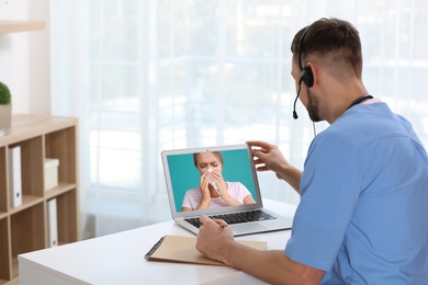 Hotline service. Doctor consulting patient online via laptop indoors
