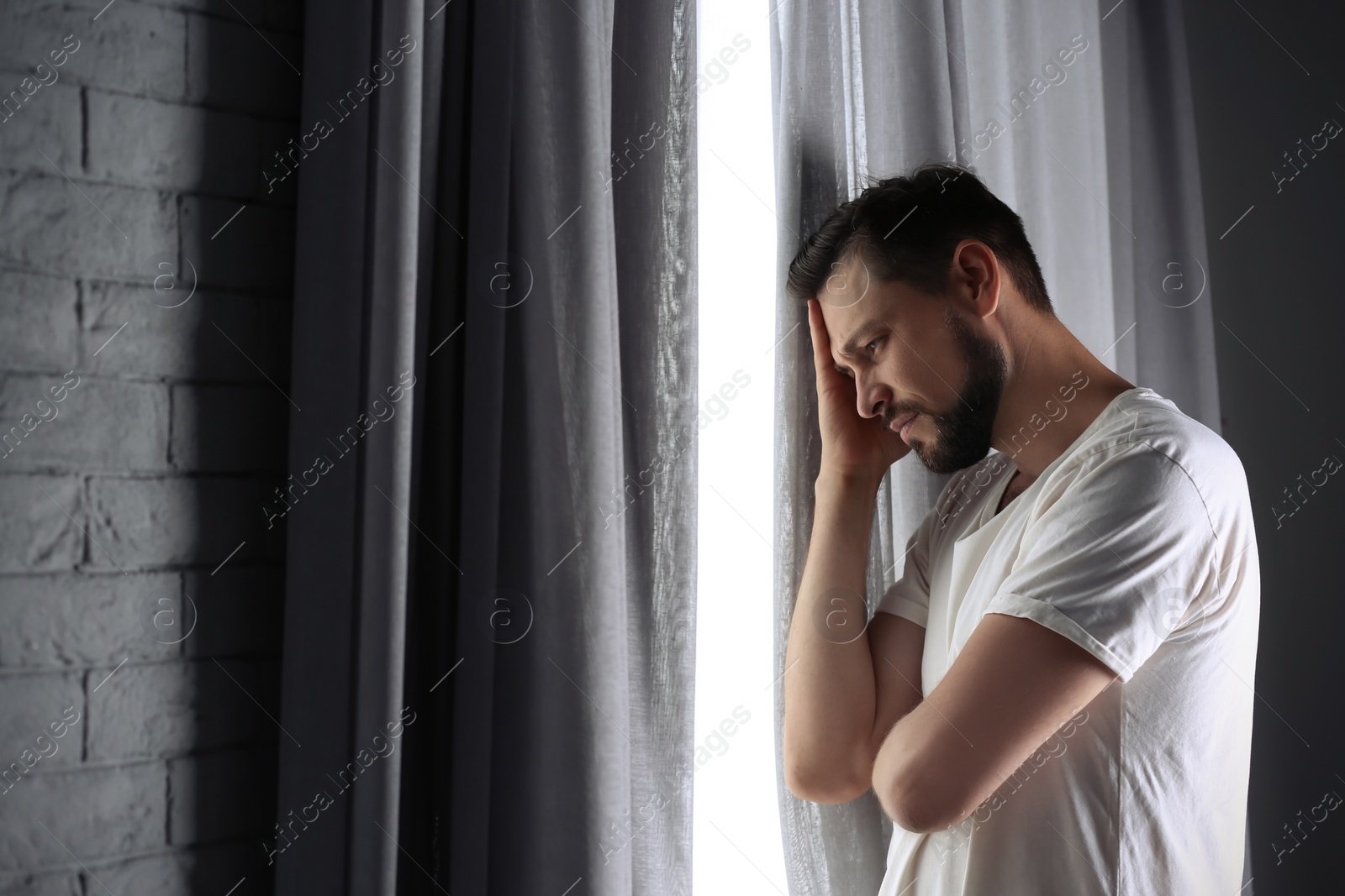 Photo of Lonely depressed man near window at home