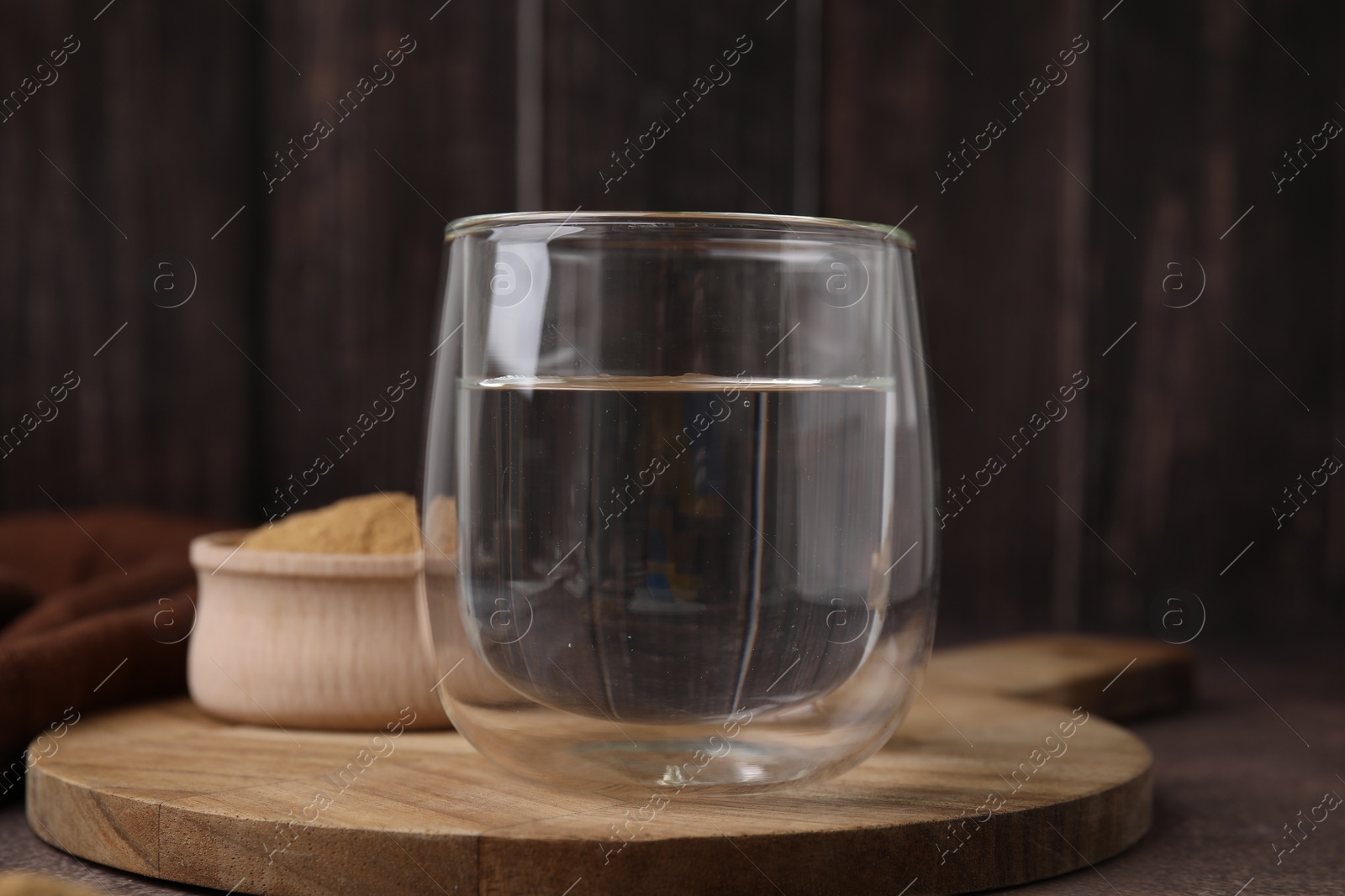 Photo of Dietary fiber. Glass of water and psyllium husk powder on brown table