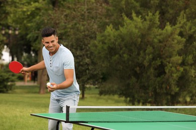 Photo of Happy man playing ping pong outdoors on summer day