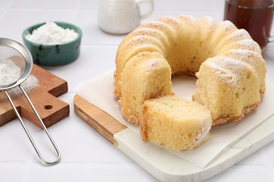 Photo of Delicious freshly baked sponge cake on white tiled table, closeup