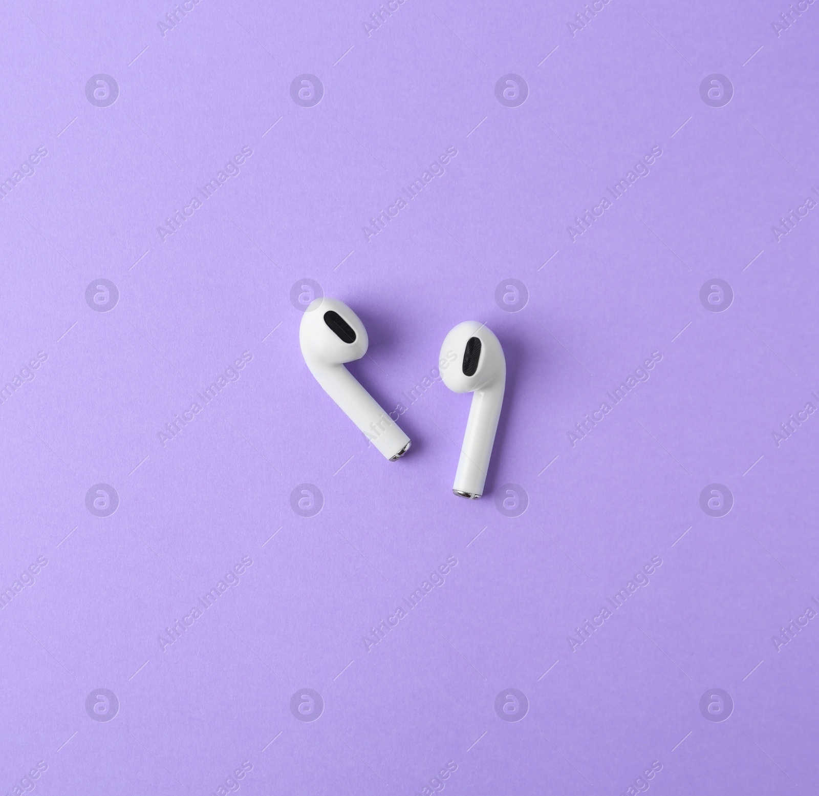 Photo of Modern wireless earphones on violet background, flat lay