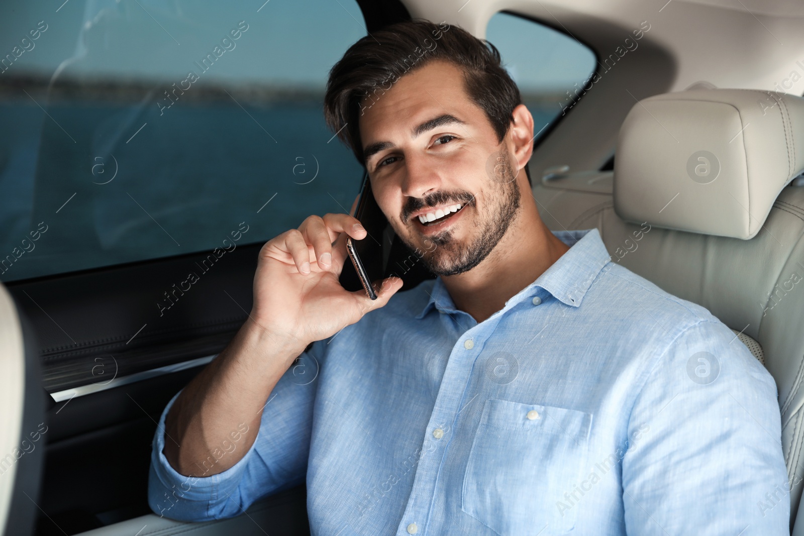 Photo of Attractive young man talking on phone in luxury car