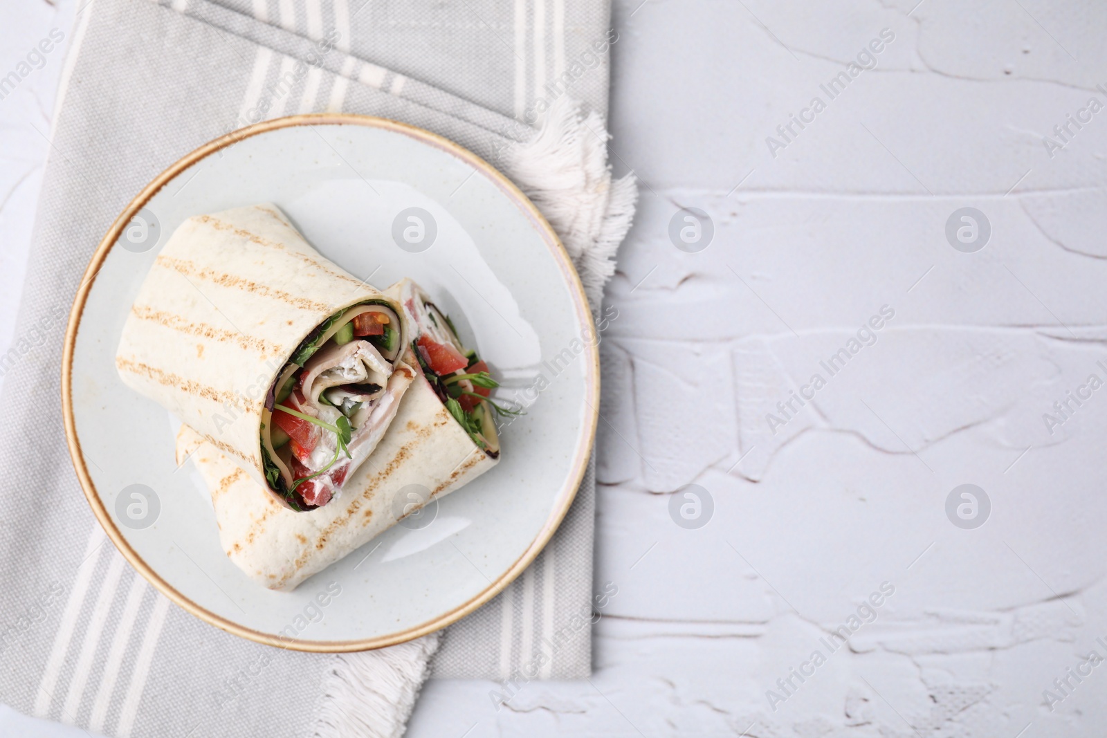 Photo of Delicious sandwich wraps with fresh vegetables on white textured table, top view. Space for text