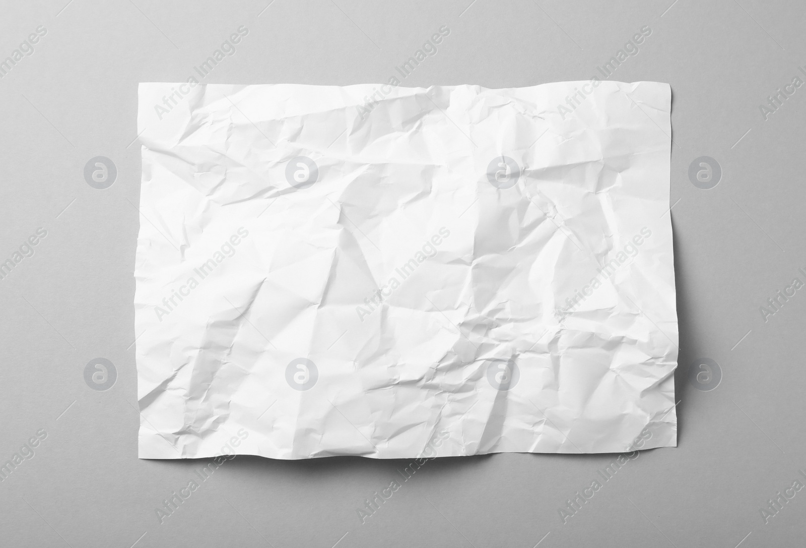 Photo of Sheet of white crumpled paper on grey background, top view