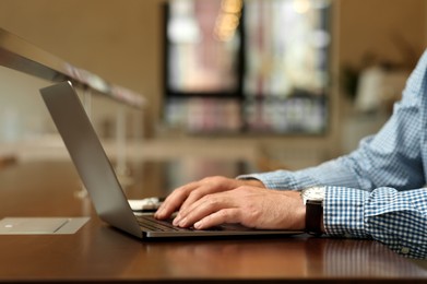 Photo of Man working on laptop at table in cafe, closeup