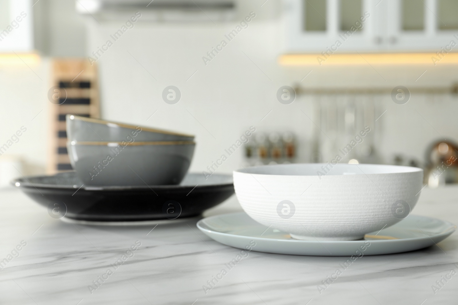 Photo of Set of ceramic tableware on white marble table in kitchen