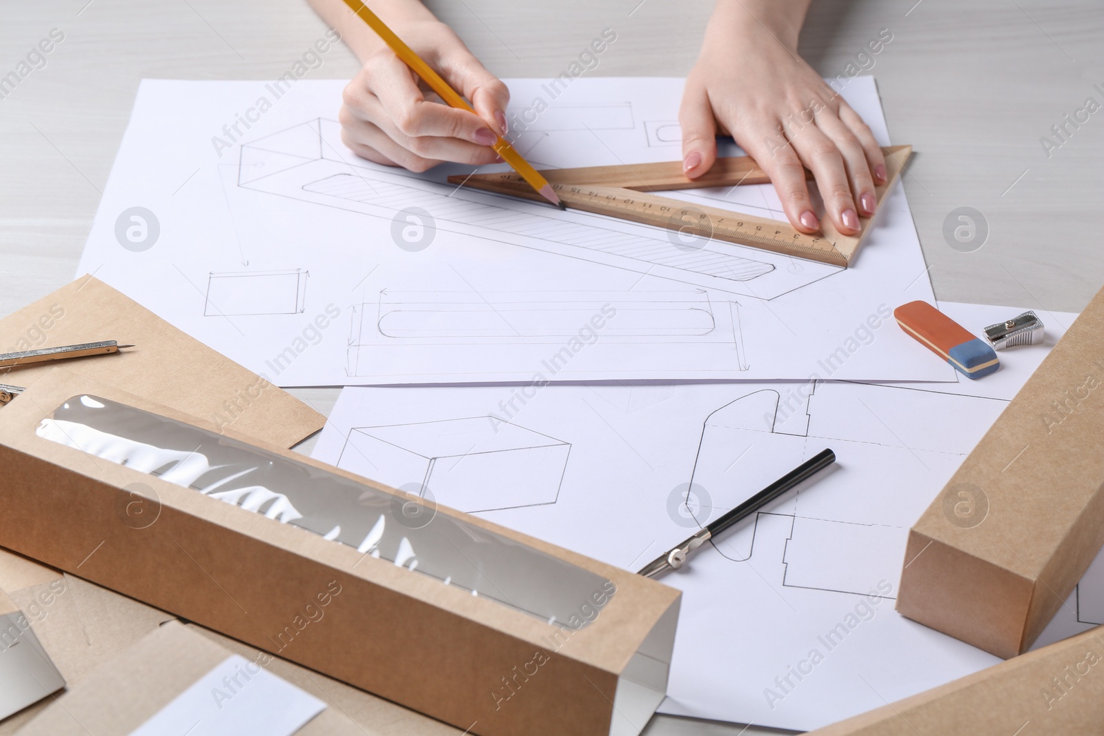 Photo of Woman creating packaging design at light wooden table, closeup