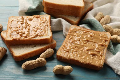 Photo of Delicious toasts with peanut butter and nuts on light blue wooden table, closeup