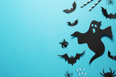 Photo of Flat lay composition with paper ghost and bats on light blue background, space for text. Halloween celebration