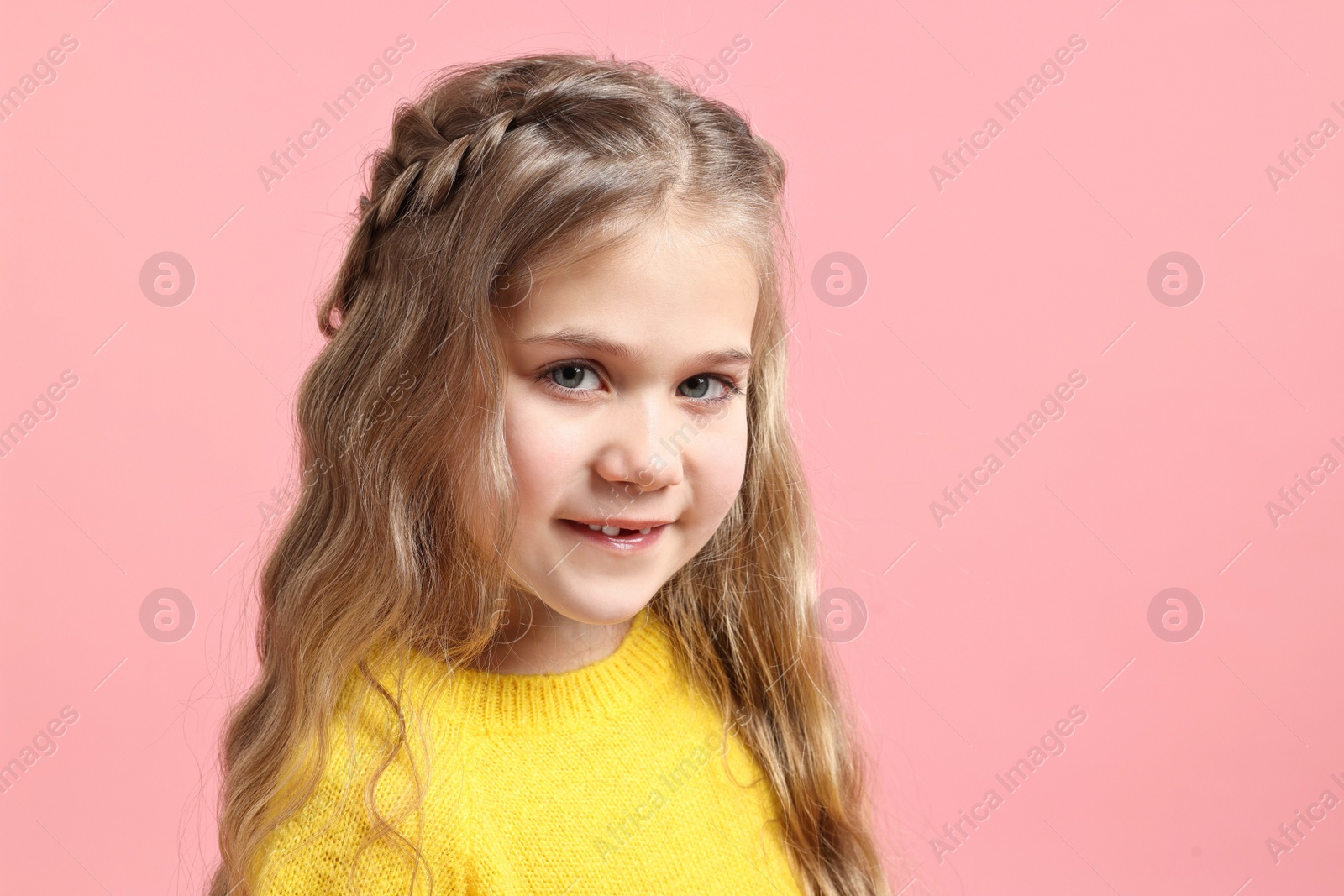 Photo of Cute little girl with braided hair on pink background