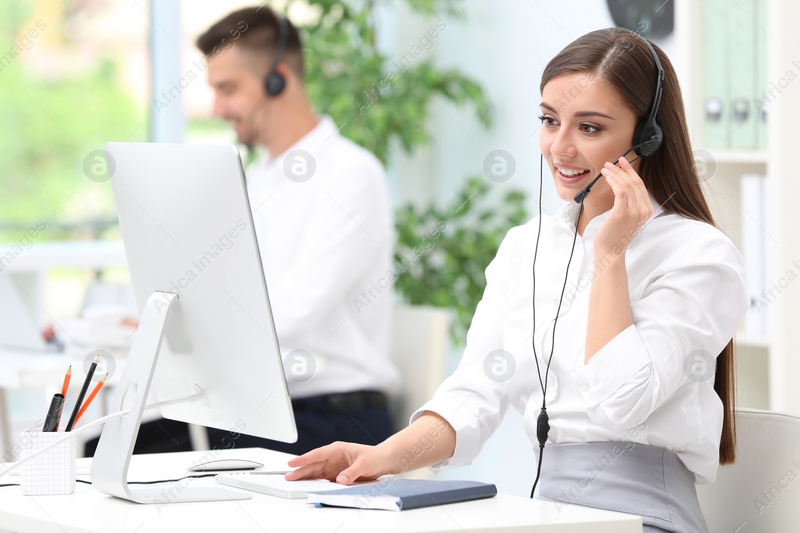 Photo of Female receptionist with headset at desk in office