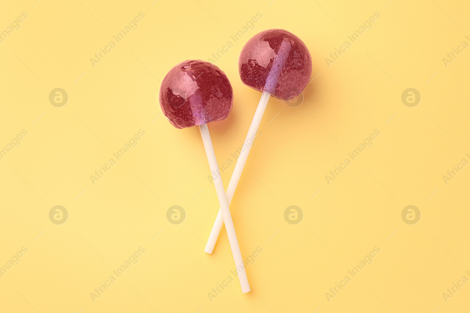 Photo of Tasty lollipops on yellow background, flat lay