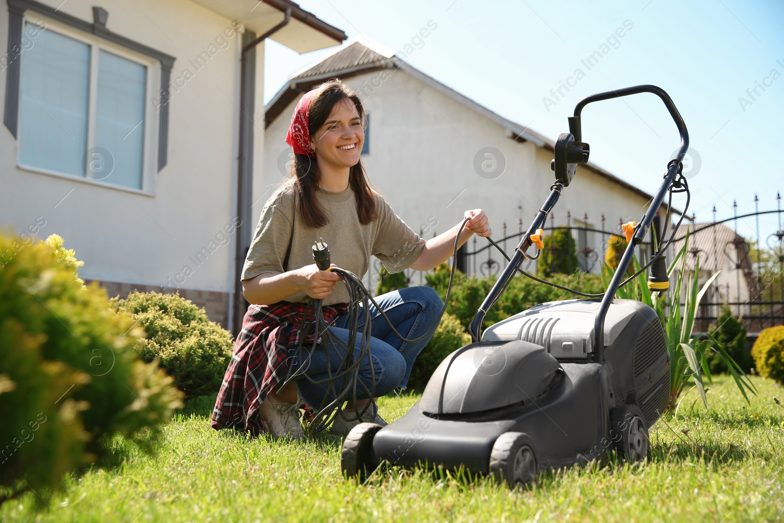 Photo of Smiling woman with modern lawn mower in garden