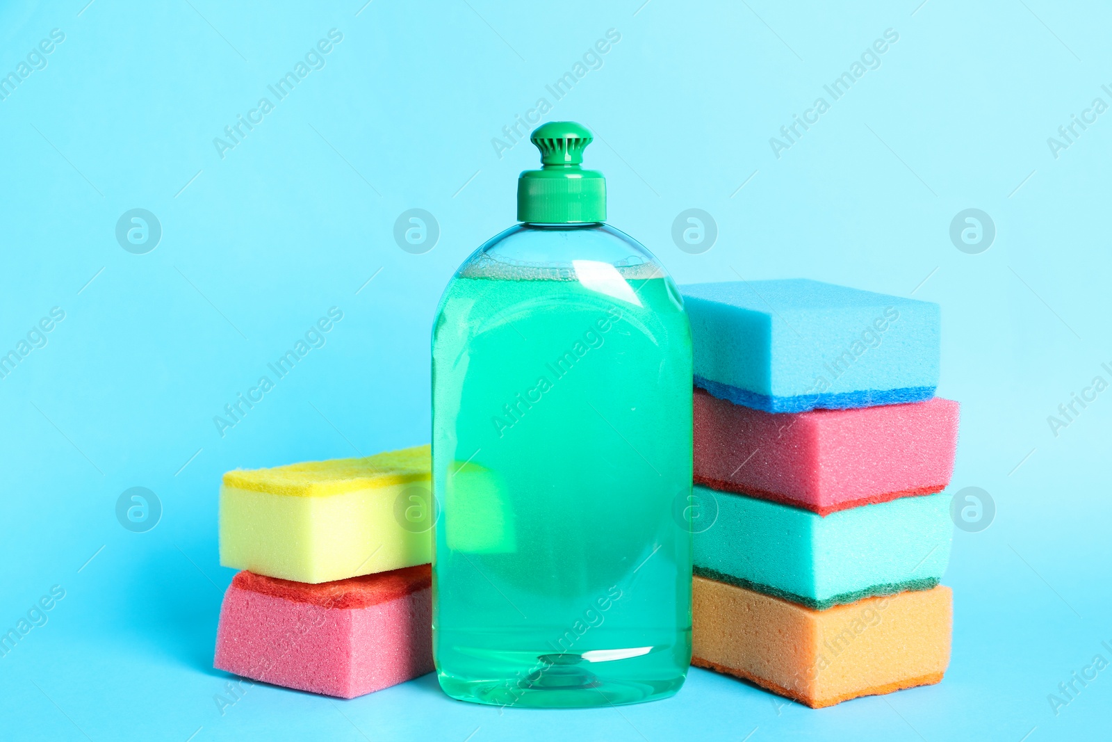 Photo of Detergent and sponges on light blue background