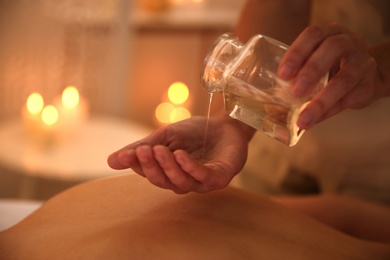 Photo of Young woman receiving back massage with oil in spa salon, closeup