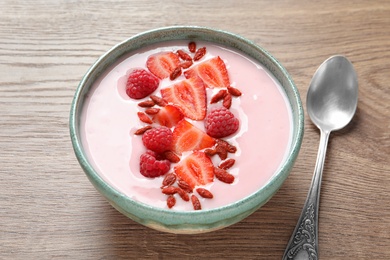 Smoothie bowl with goji berries and spoon on wooden table