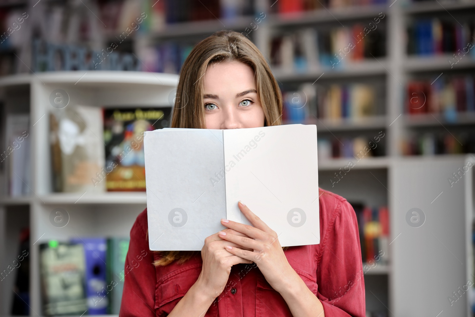 Photo of Young pretty woman with book in library