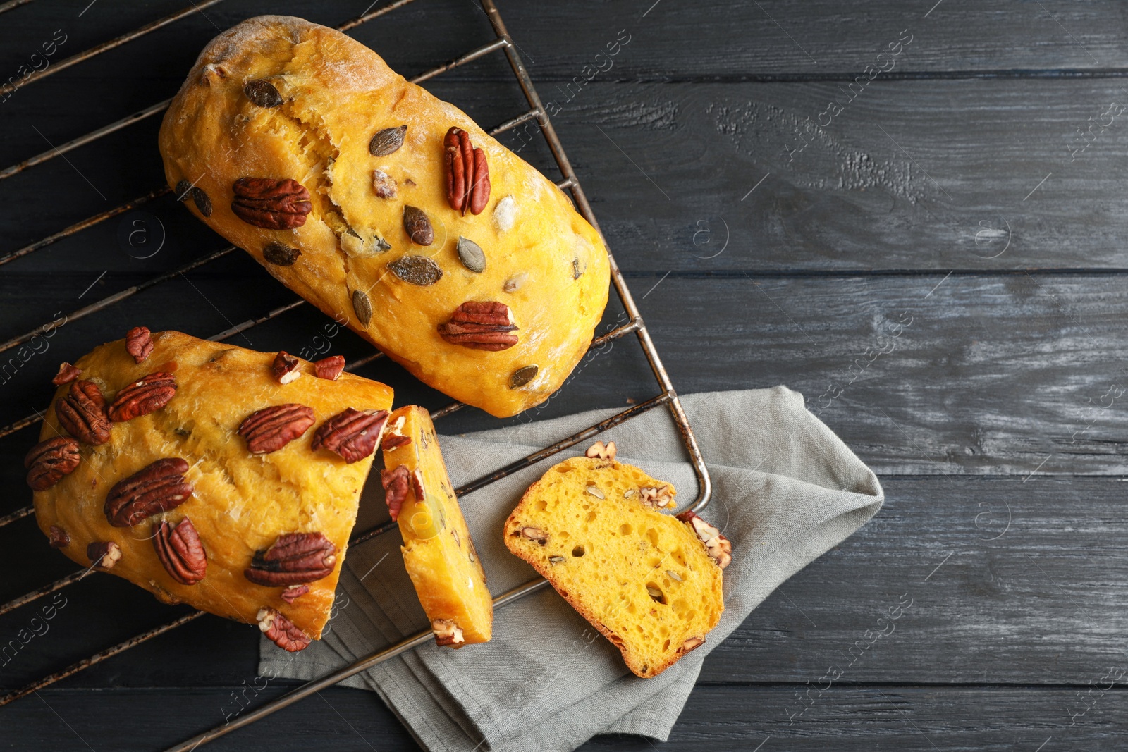 Photo of Delicious pumpkin bread with pecan nuts on black wooden table, flat lay. Space for text