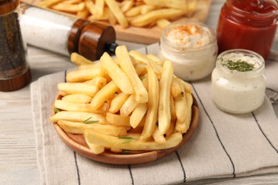 Delicious french fries served with sauces on light wooden table, closeup