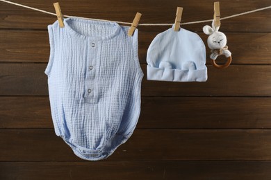 Photo of Baby clothes and accessories hanging on washing line near wooden wall