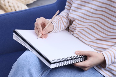 Photo of Young woman drawing in sketchbook on sofa, closeup