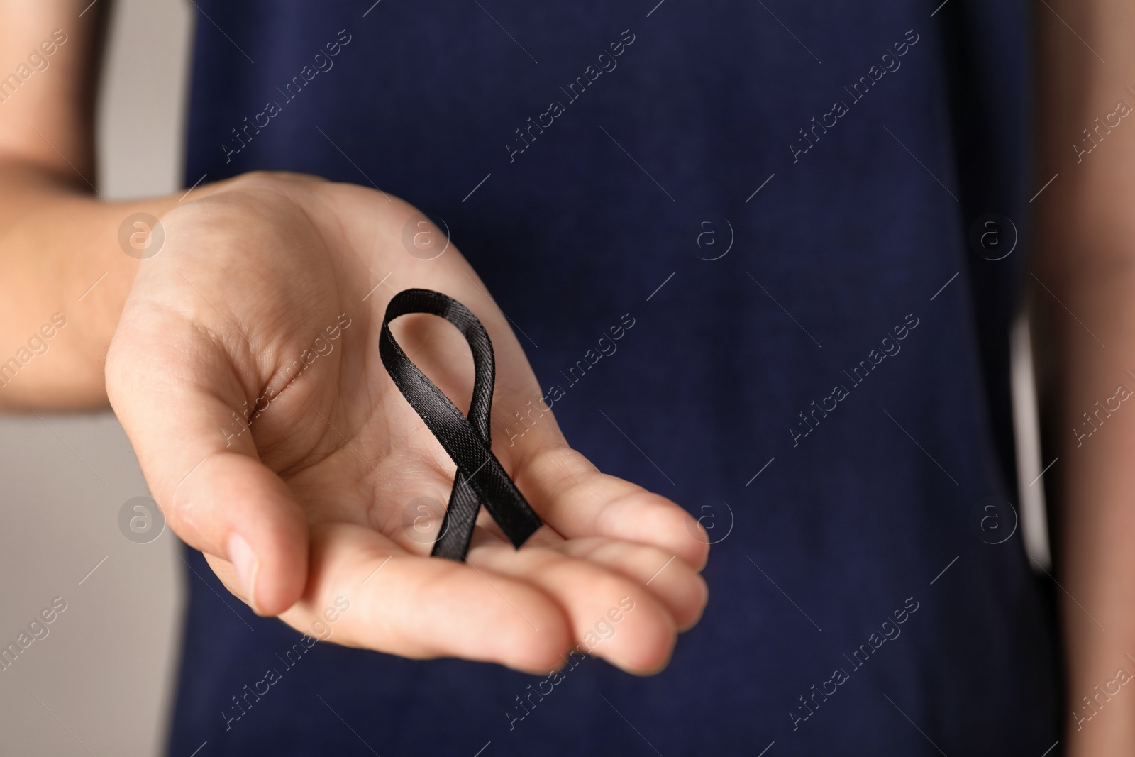 Photo of Young woman holding black ribbon, closeup. Funeral symbol