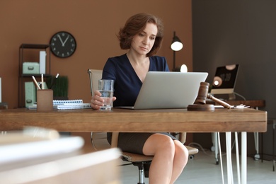 Photo of Female lawyer working with laptop at table in office
