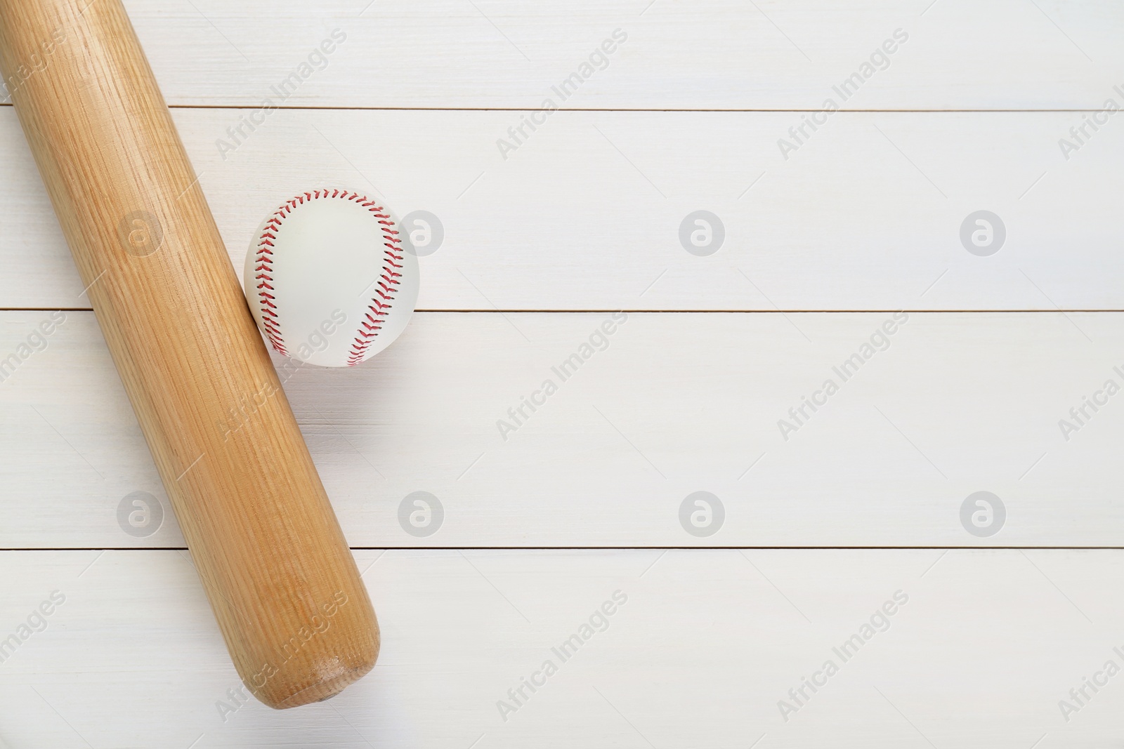 Photo of Baseball bat and ball on white wooden table, top view with space for text. Sports equipment