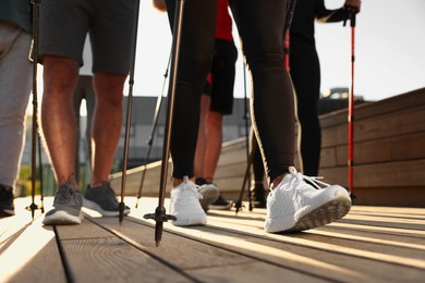 Photo of Group of people practicing Nordic walking with poles outdoors, closeup