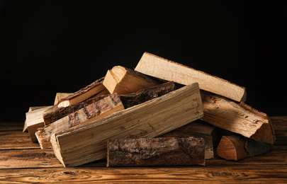 Cut firewood on table against black background