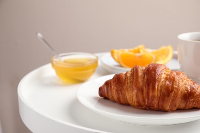 Photo of Delicious breakfast with croissant and honey on white table