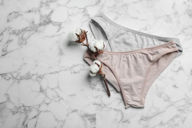Photo of Women's underwear and cotton flowers on marble background, flat lay. Space for text