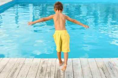 Photo of Little child near outdoor swimming pool. Dangerous situation