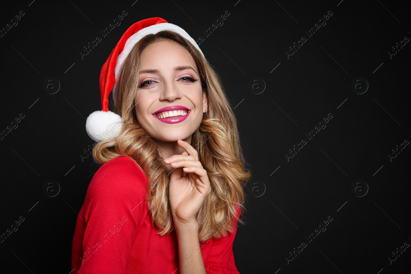 Photo of Happy woman in Santa hat on black background, space for text. Christmas party