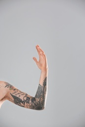 Photo of Man's arm with stylish tattoos on grey background